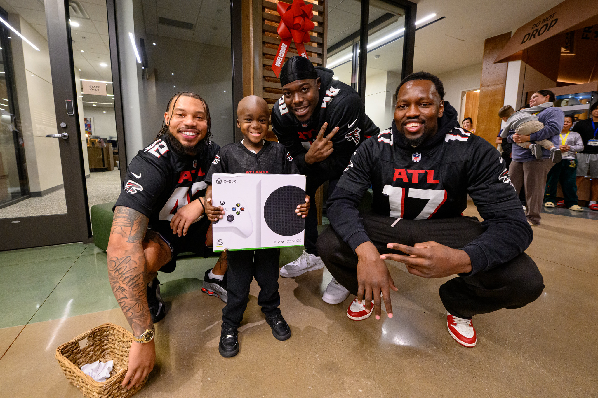 3 guys standing with a boy holding an XBOX