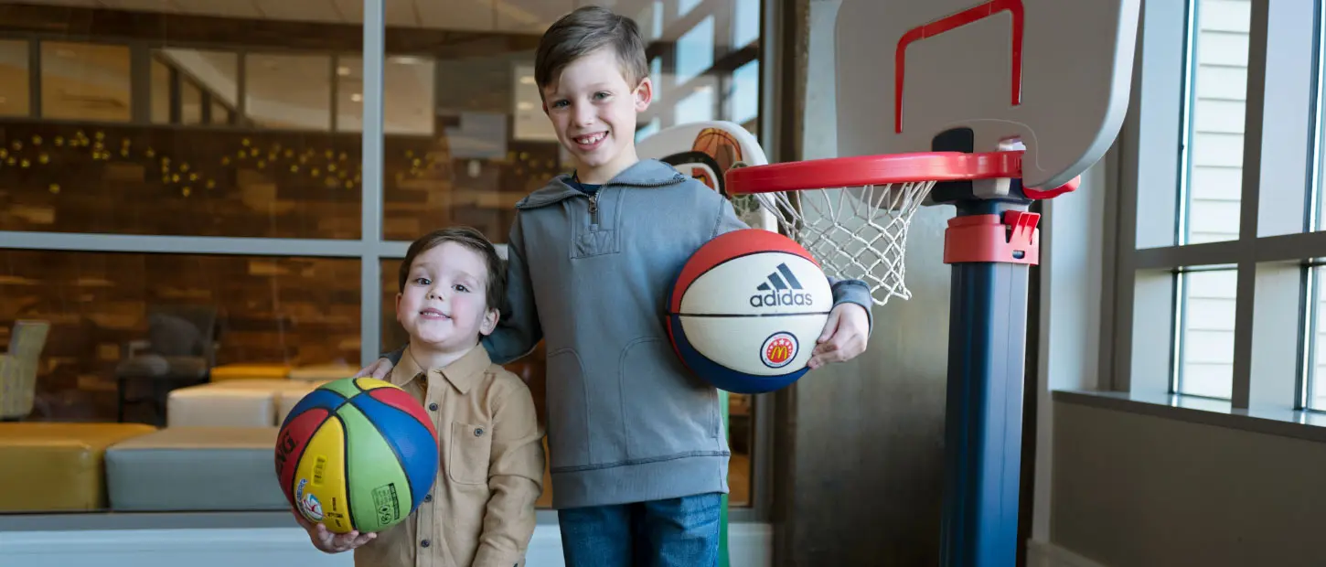two boys holding basketballs smiling