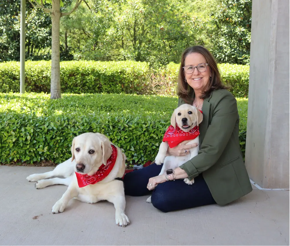 Ronald McDonald house Atlanta CEO sitting outside with two therapy dogs