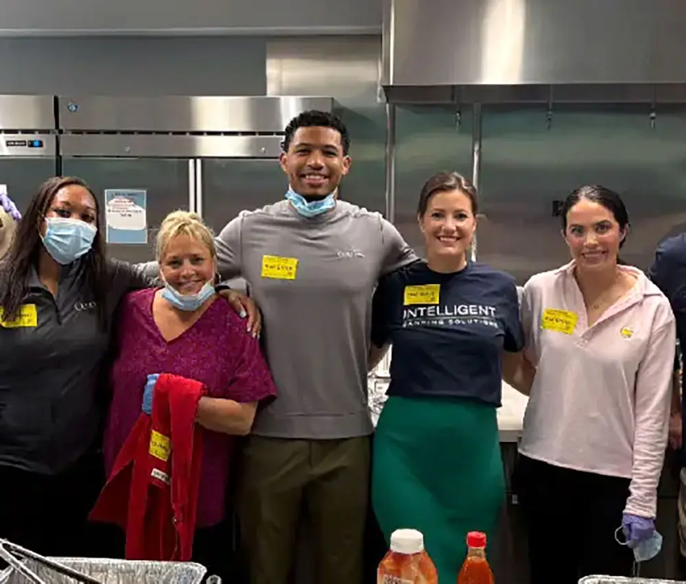 Group of people standing in kitchen smiling