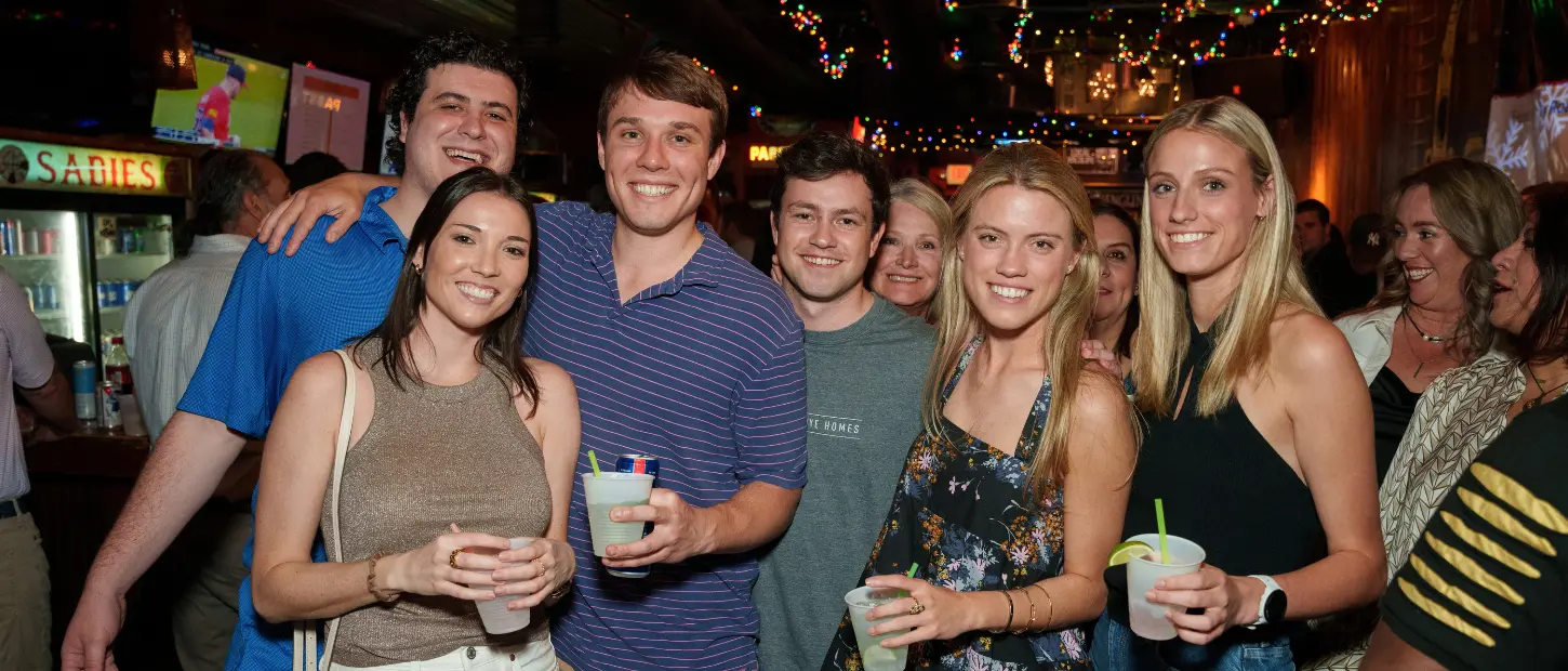 group of people standing together smiling at a bar