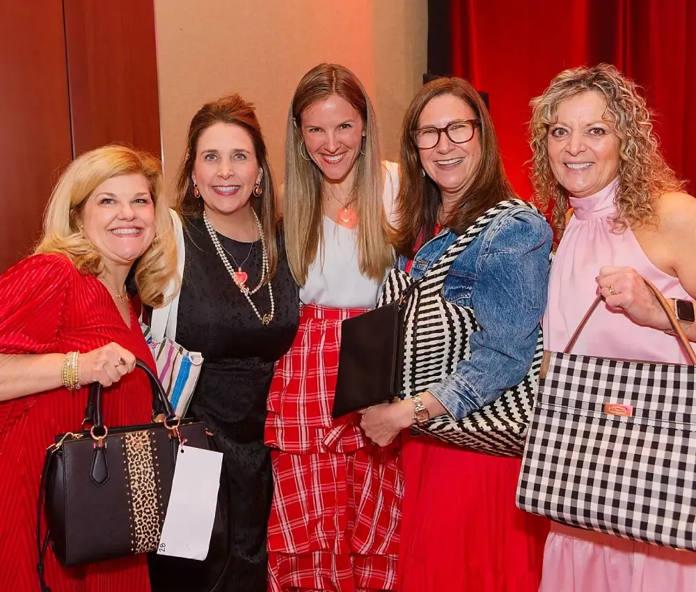women standing holding purses