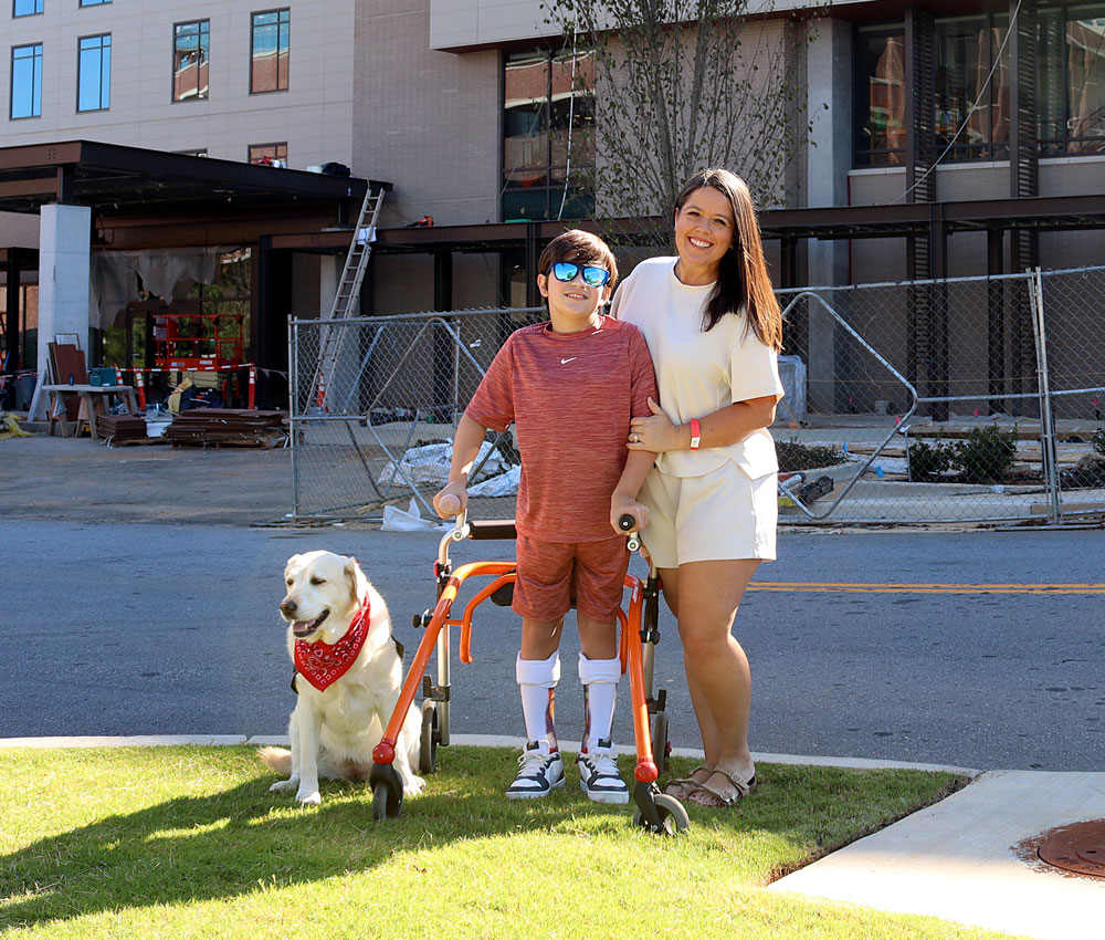 woman and boy standing in front of house with dog