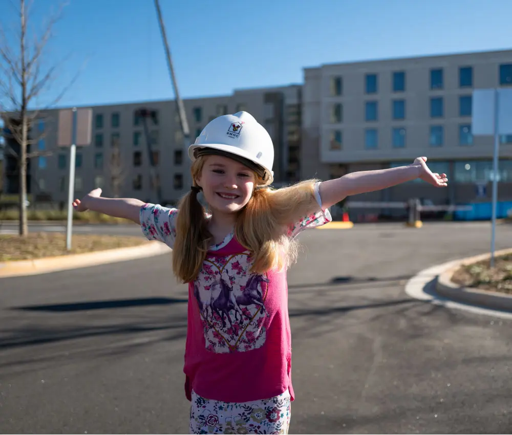 girl holding arms out in front of a building