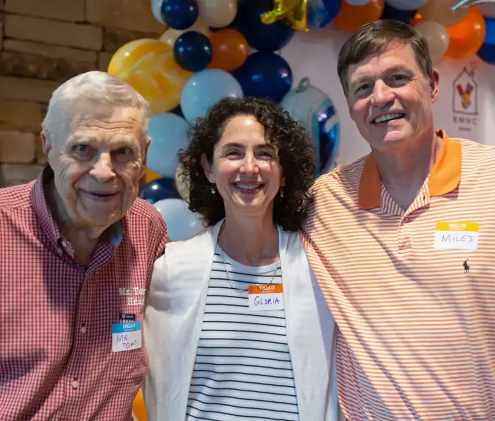 two men and a woman standing together smiling