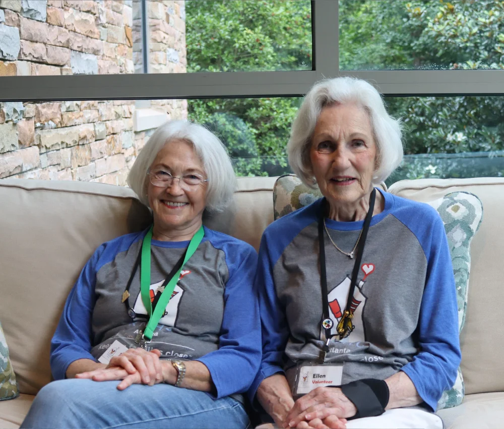 two women sitting on a couch smiling