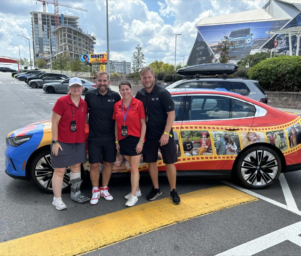 group of people standing in front of BMW car in parking lot