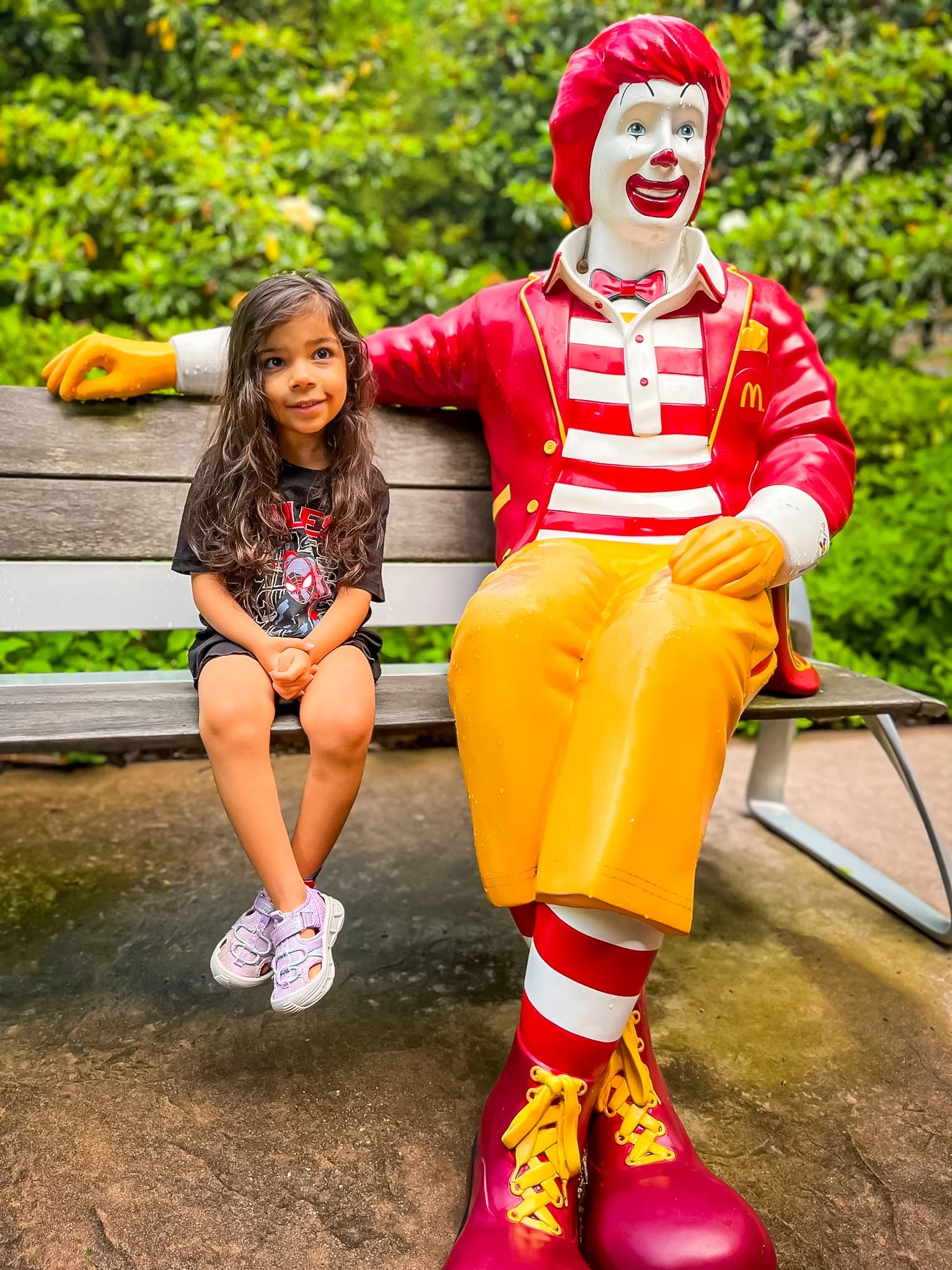 girl sitting on bench with Ronald
McDonald statue