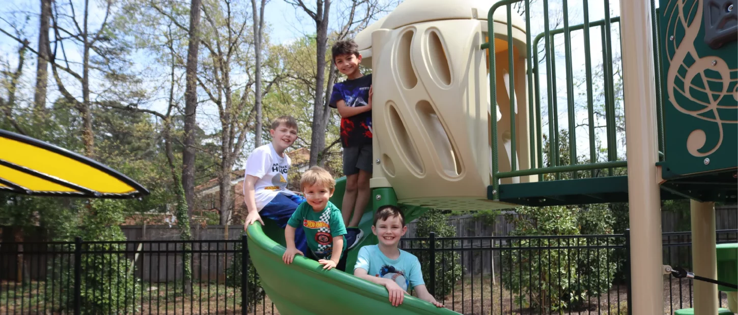 four kids on slide smiling