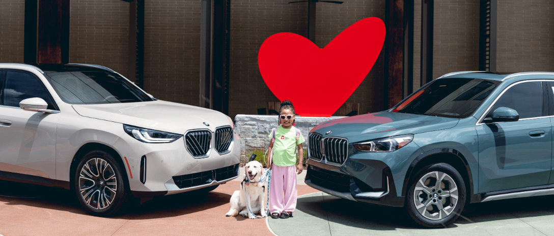 girl standing with dog between two cars