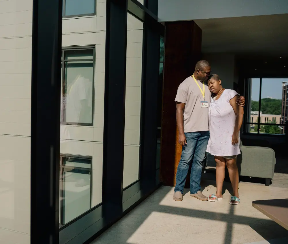 man hugging girl by window