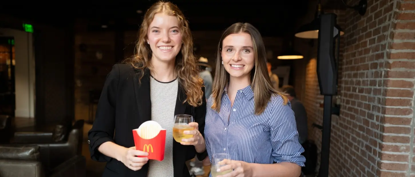 two women holding wine and fries