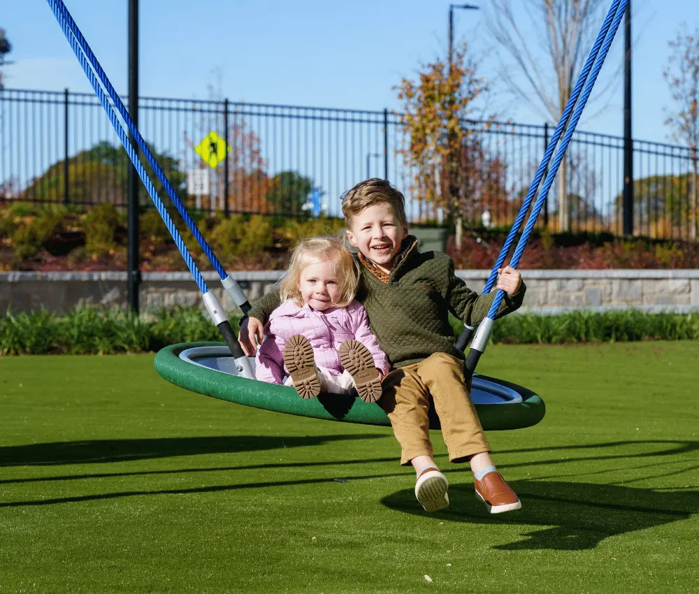girl and boy sitting on swing