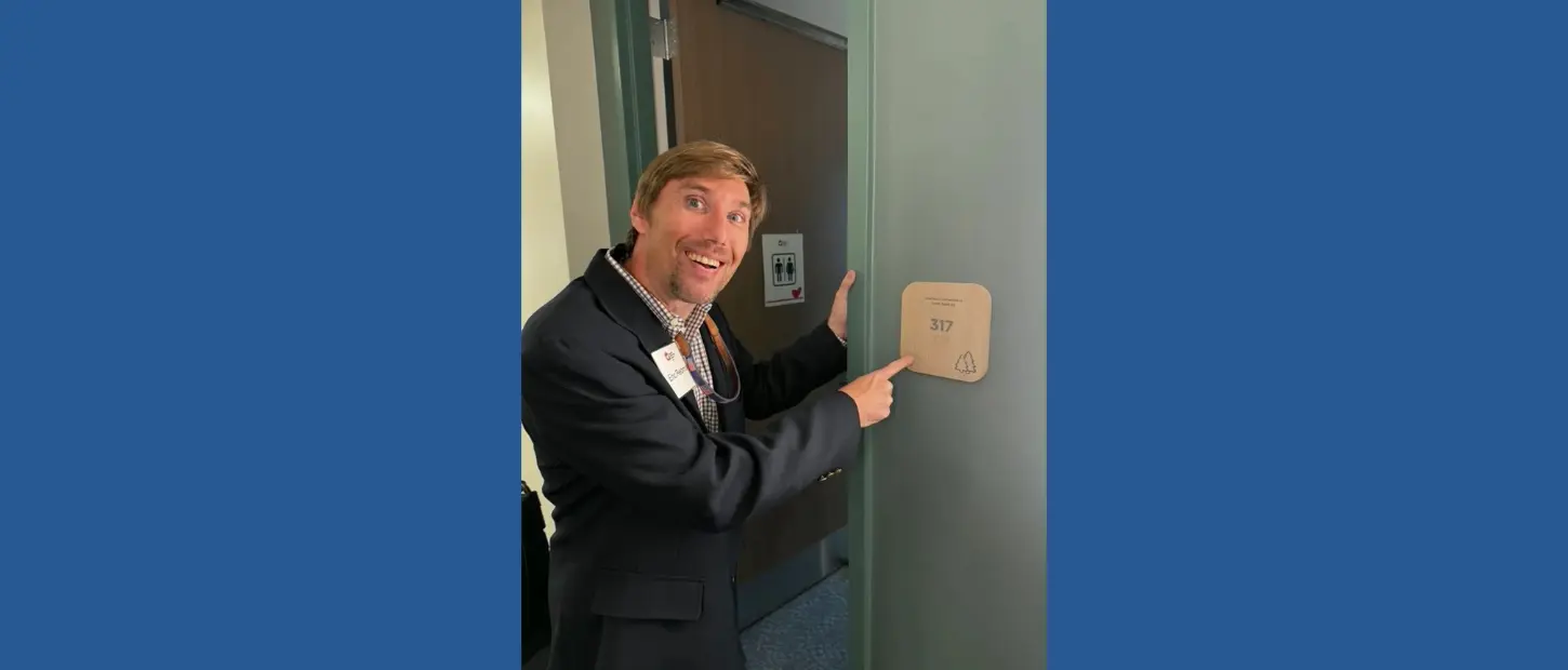 man smiling next to sign