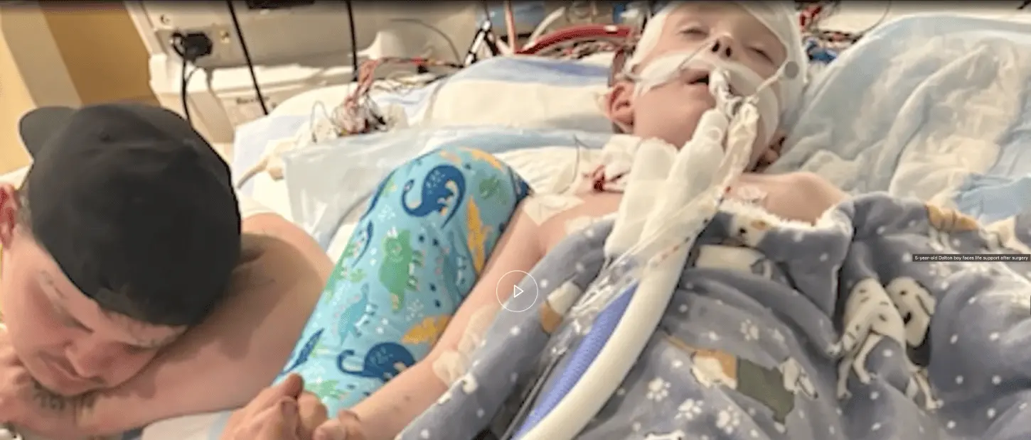 dad laying beside boy in hospital bed