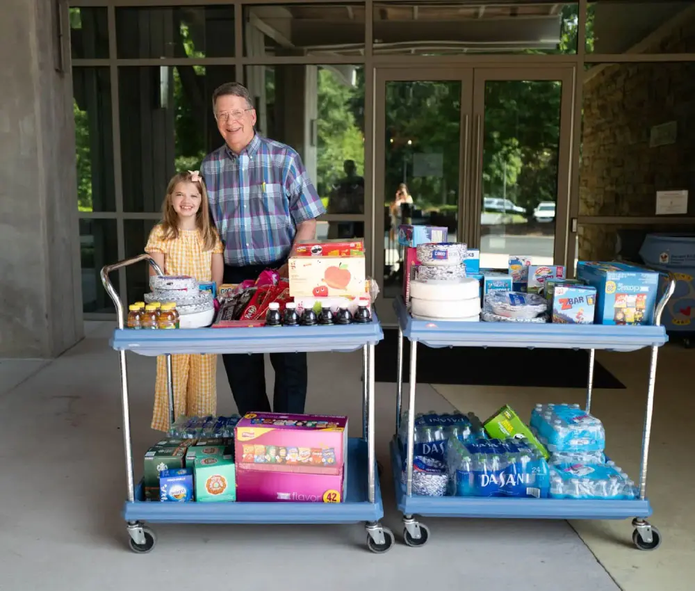 man and girl standing behind cart of items